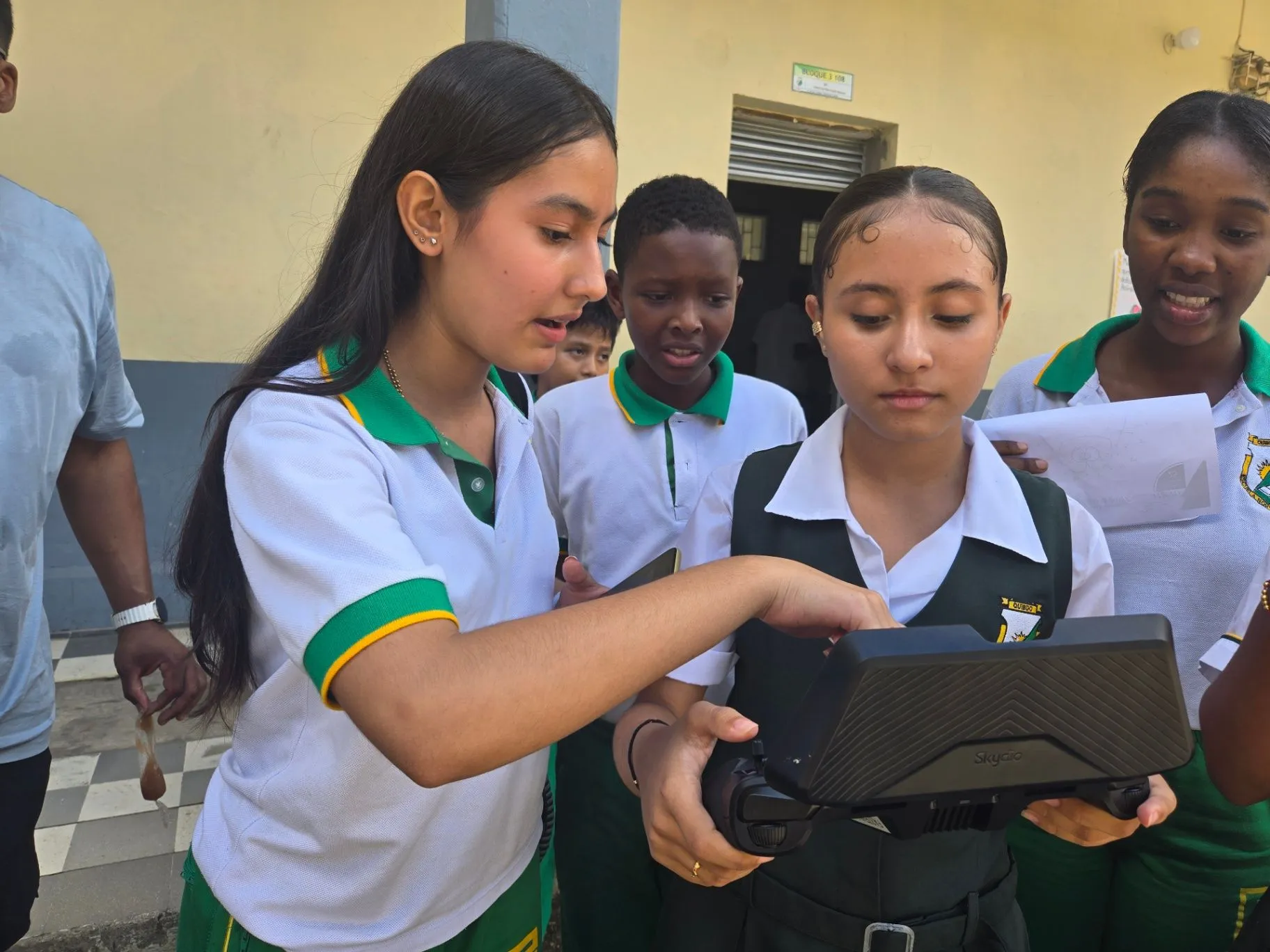 Students in green-and-white school uniforms gathered around a SkyRover drone controller