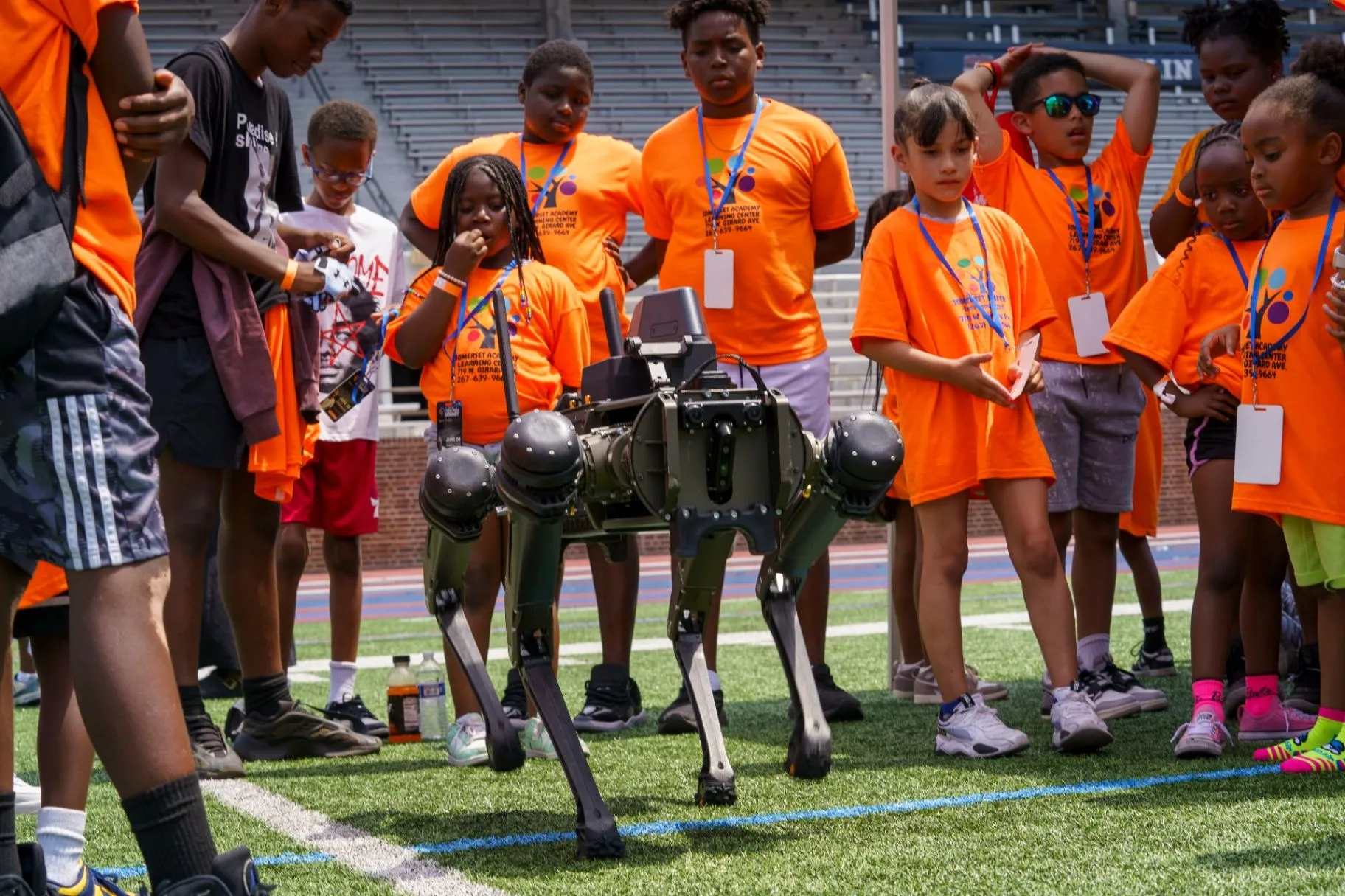 Students gathered around a four-legged robotics dog on the field